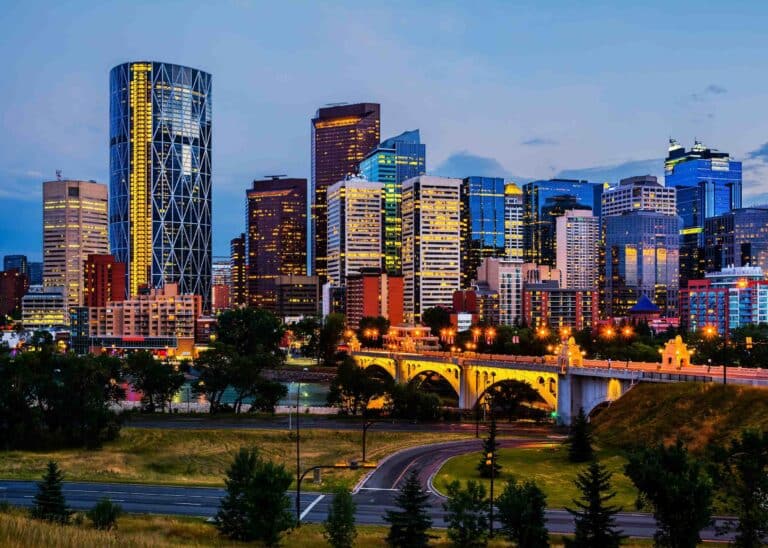 Downtown Calgary towers lit up at dusk above the Centre Street Bridge