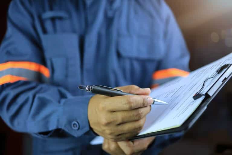 An inspector filling in a condition checklist on a clipboard