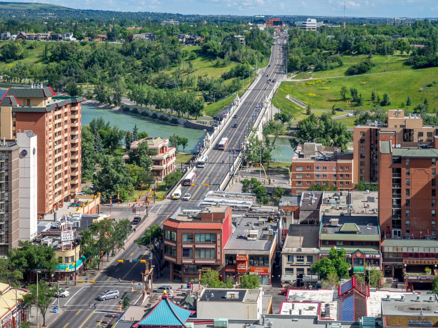 Aerial view of a Calgary river valley with green parkland and low rise apartment buildings