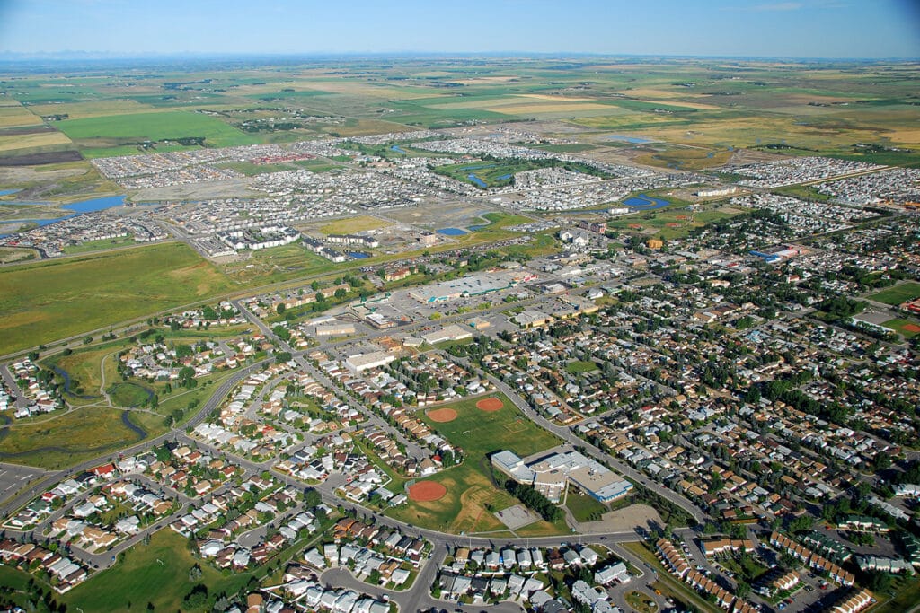 Aerial view of Airdrie neighbourhoods, a school field and farmland beyond