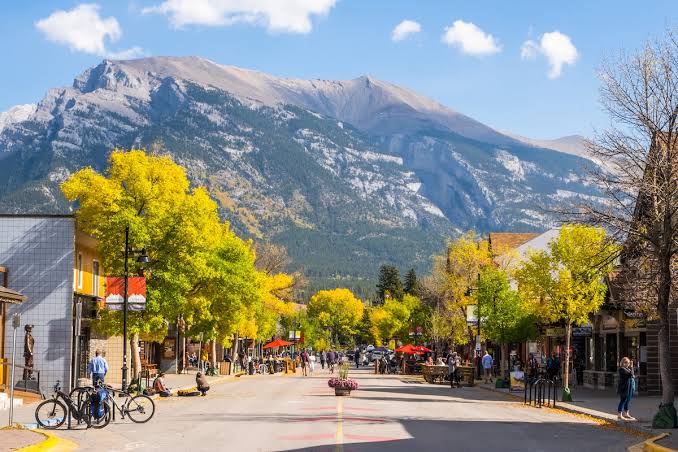 Main street in Canmore, Alberta, with autumn trees, shops and the mountains behind
