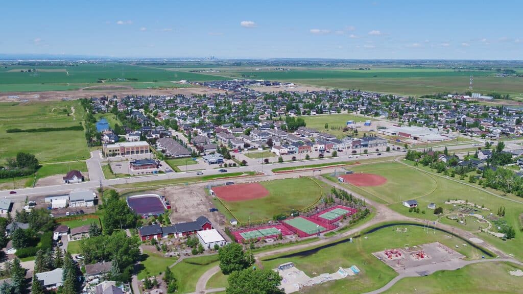 Aerial view of Langdon, Alberta, with homes, sports fields and a playground, and farmland beyond