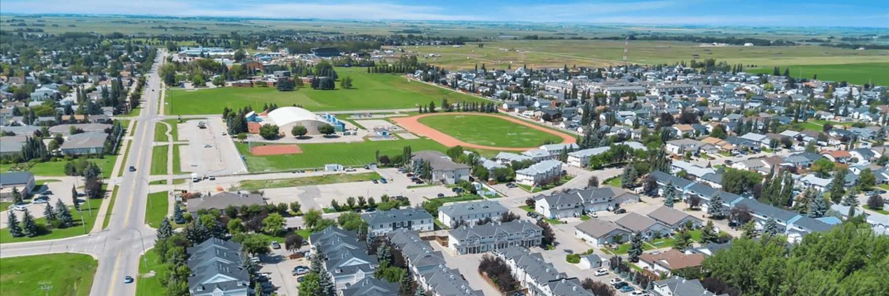 Aerial view of Strathmore, Alberta, with homes, sports fields and open prairie beyond